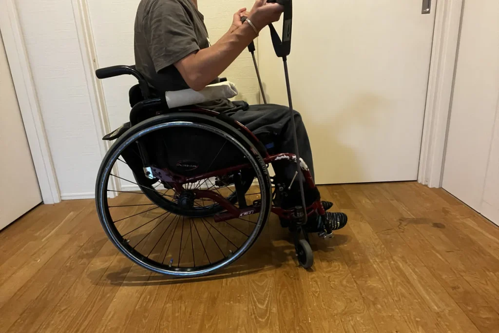 車いす上でトレーニングチューブを引く様子